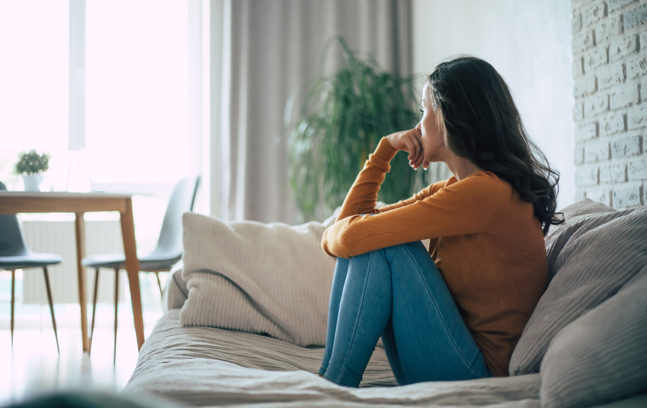 Sad woman in deep depression is sitting on the couch and crying and thinking about the bad thing